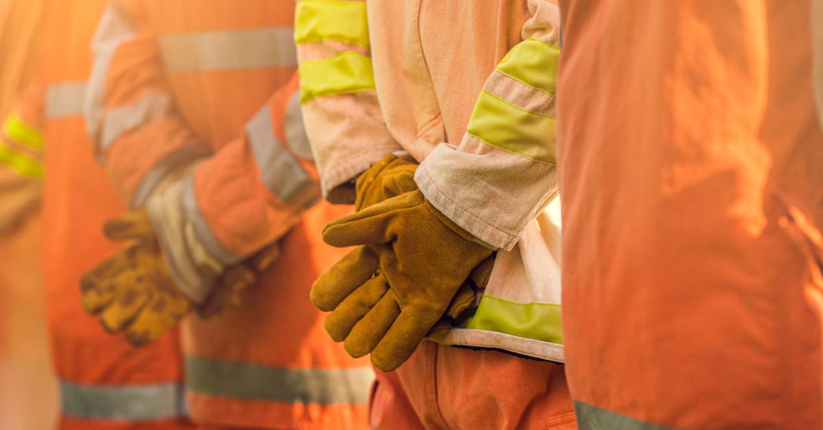 A close-up of people with hands behind their backs, wearing gloves. They're wearing coats and pants.