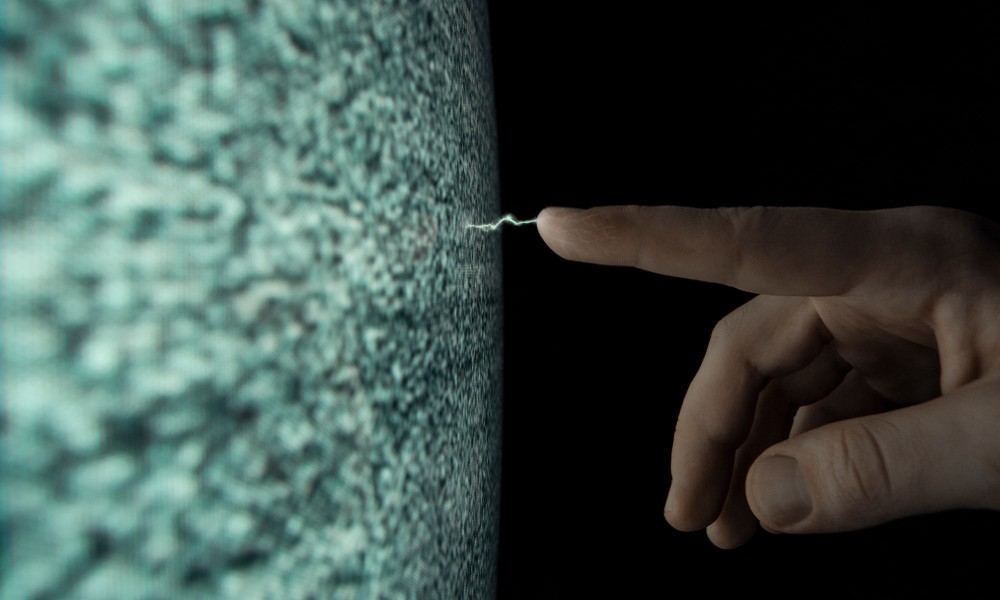 A person sticking out their hand and pointing their index finger at a an object with static electricity coming off of it.